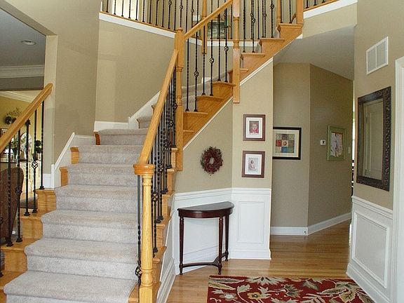 Dramatic two-story foyer with hardwood floors and wrought-iron ballasters