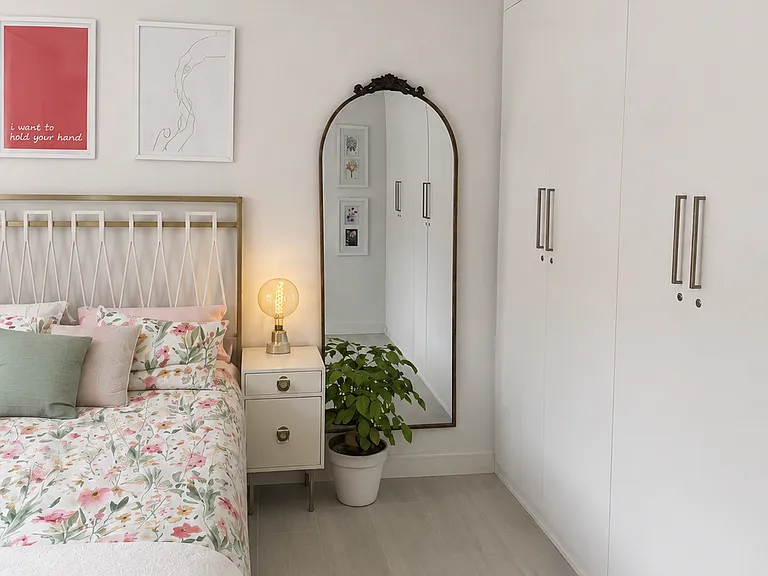 A cozy, beautifully finished bedroom with floral accents, warm brass details, generous natural light, and a polished, welcoming feel.