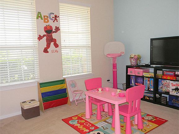 Room currently being used as a playroom features carpet flooring and large windows allowing lots of natural light.