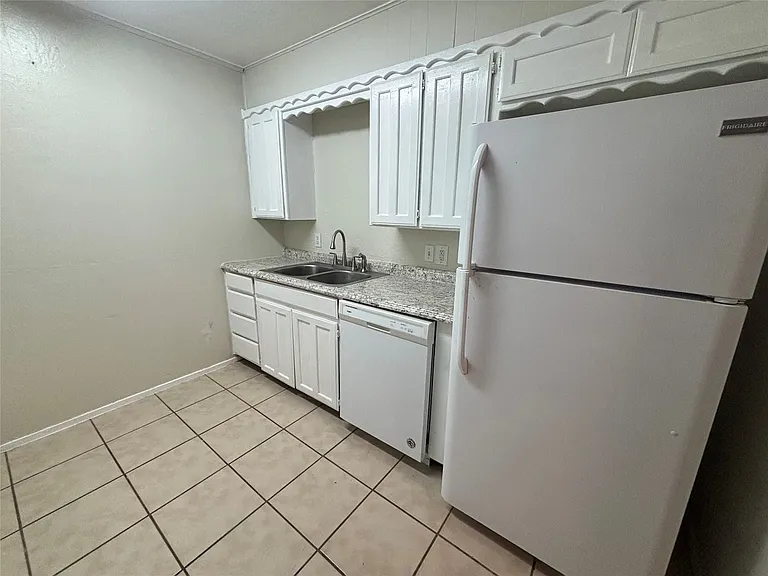 Kitchen featuring white cabinetry, light-colored countertops, a double basin sink with a gooseneck faucet, a white dishwasher, and tile flooring