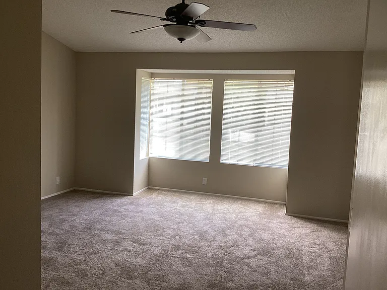 Master bedroom with bay window and ceiling fan.