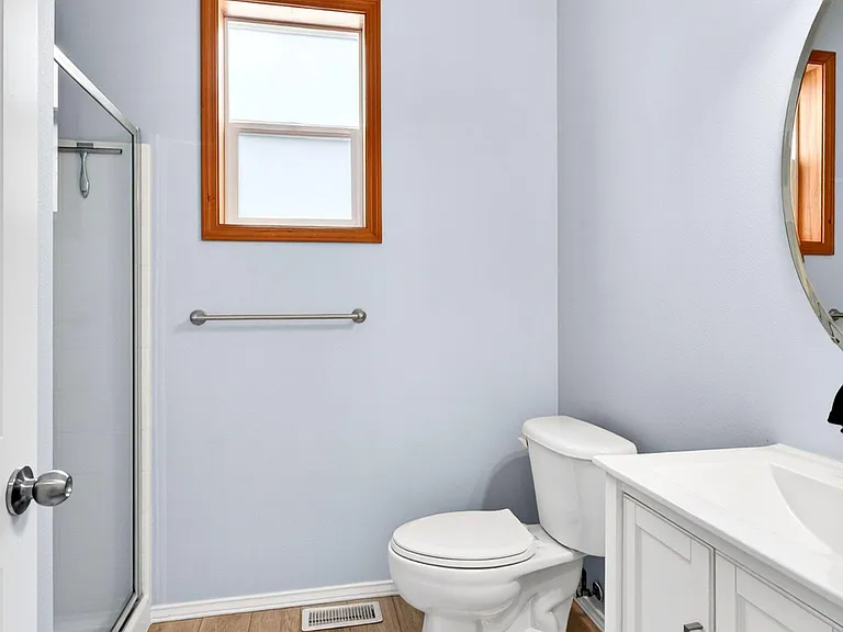 Full bathroom with a walk-in shower, single-sink vanity with storage, and a window for natural light and ventilation.