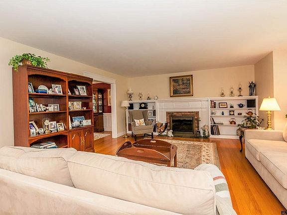 Large living room with hardwood flooring and a wood-burning fireplace.