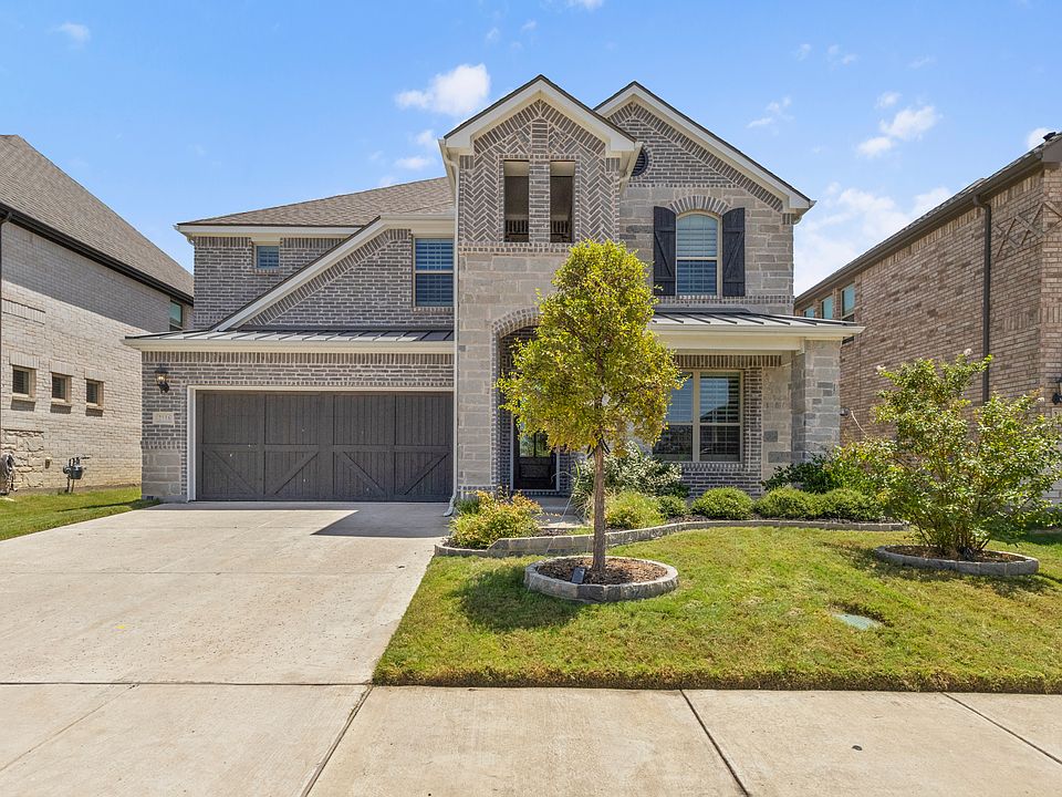 Front of the home with brick and stone siding, 2-car garage, driveway and a front lawn
