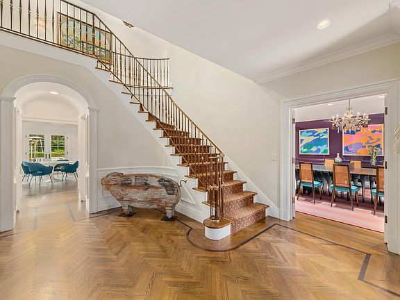Entry foyer with herringbone floors and custom millwork and architectural design. This photo has been virtually staged.