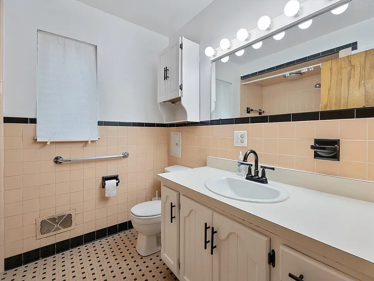 Full bathroom has excellent lighting, modern fixtures and extra large mirror