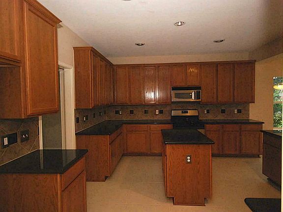 Spaicous island kitchen with granite counter tops, tile back splash with black granite inlays.