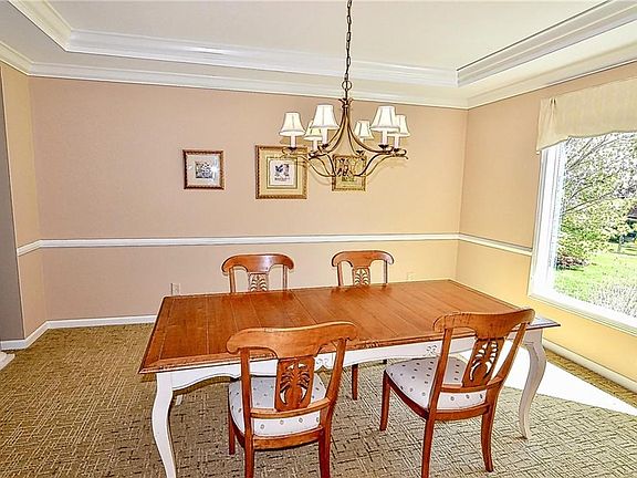 Formal dining room has a view of the private backyard through the large picture window and includes chair rail, tray ceiling and crown molding.