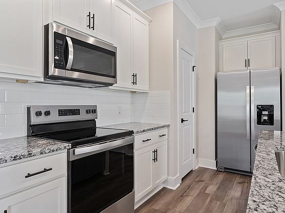 The kitchen has stainless steel appliances and plank flooring.
