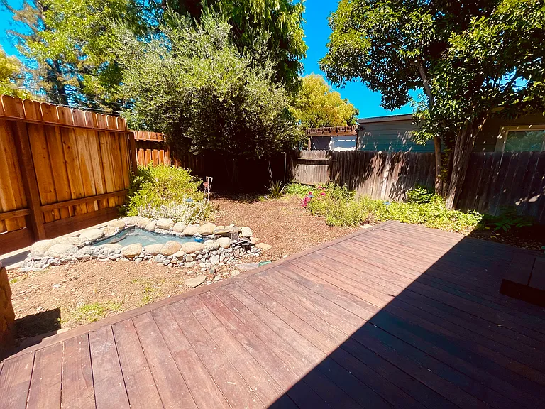Backyard with redwood deck, lighting, tranquil pond, and automatic sprinklers