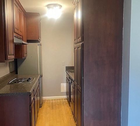 Nice galley kitchen with Mahogany cabinets, refrigerator, dishwasher, stove top, and convection oven.