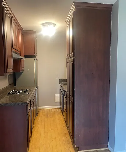 Nice galley kitchen with Mahogany cabinets, refrigerator, dishwasher, stove top, and convection oven.