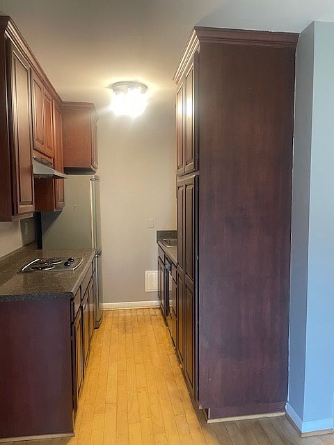 Nice galley kitchen with Mahogany cabinets, refrigerator, dishwasher, stove top, and convection oven.