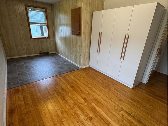 Bedroom 1. A king size bed fits in the space with linoleum. Window faces east, into the back yard.