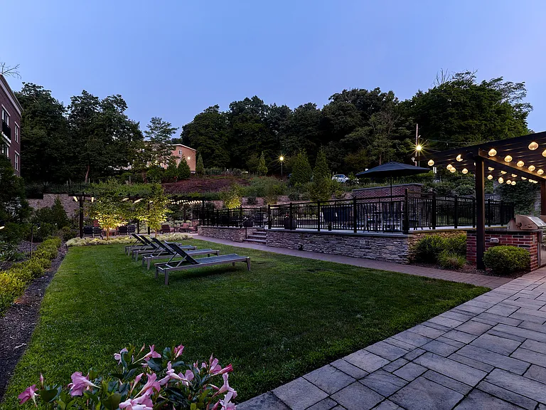 Enjoy our charming outdoor area with lush greenery, inviting patio seating, and cozy string lights, ideal for relaxing evenings.