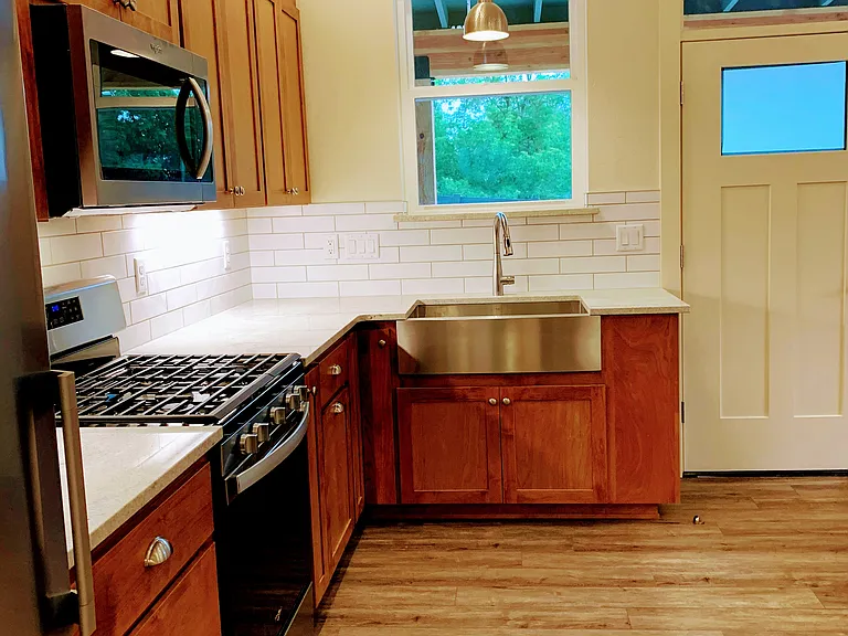 Open kitchen with fridge, gas stove and microwave.