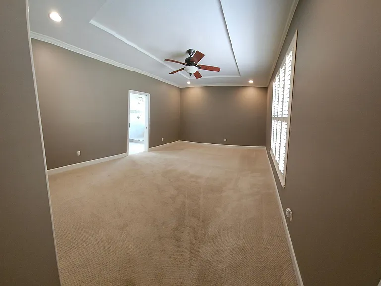 Master bedroom with ceiling fan, large windows, and upgraded lighting.