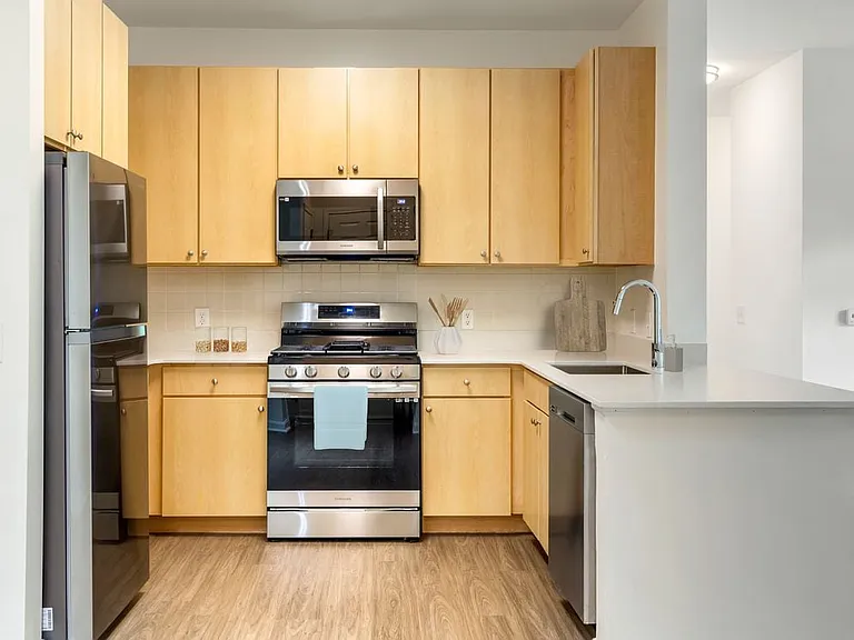 Classic Package III kitchen light oak cabinetry, white quartz countertop, beige subway tile backsplash, stainless steel appliances, and hard surface flooring
