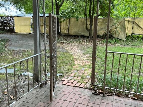 looking out front door; small porch area; car parking pad; gated yard