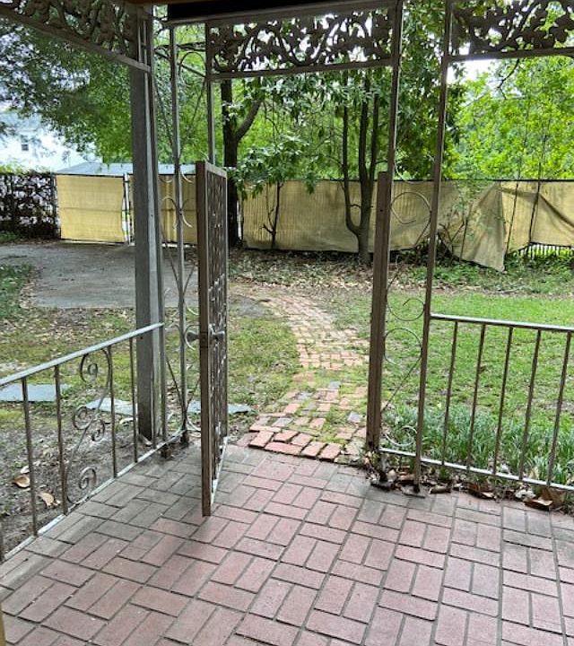 looking out front door; small porch area; car parking pad; gated yard