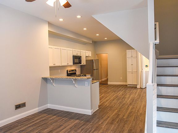 kitchen/dining space with gray vinyl flooring, stainless steel appliances, tons of cabinet space, pantry, granite countertops, and bar height countertops for extra seating
