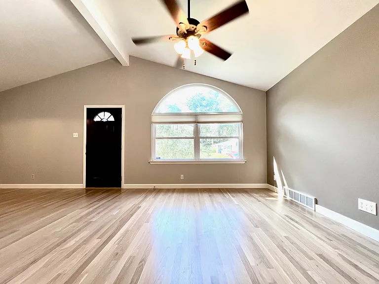 Sunny living room with cellular privacy shades and overhead fan.