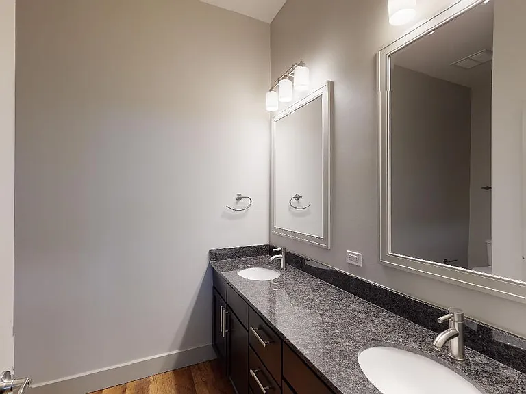 Apartment bathroom with wood-style flooring and double sinks.