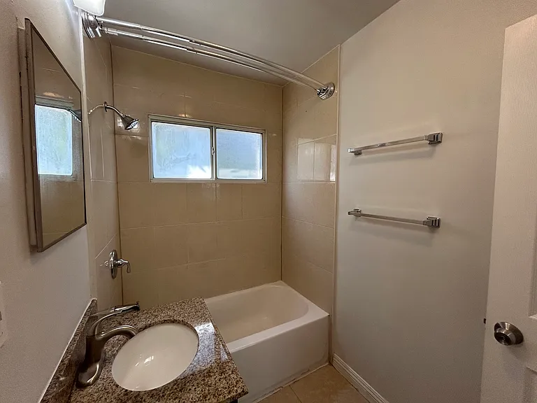 Double towel racks, curved shower rod, new faucet and shower head, natural light from window.