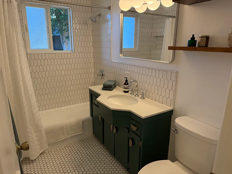 Charming vintage vanity with new sink, faucet and solid quartz countertop. All new tiled shower, backsplash and floor.