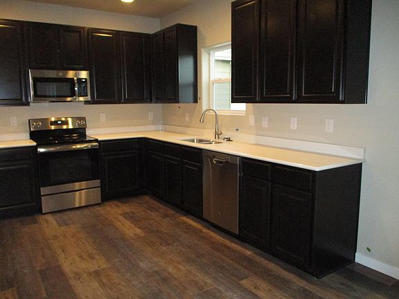 Kitchen with warm, dark cabinetry, stainless steel appliances and quartz counter top.