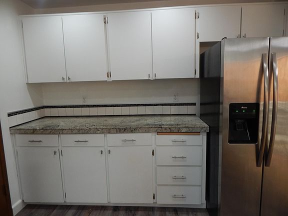 Granite countertops and stainless steel side by side refrigerator with water and ice