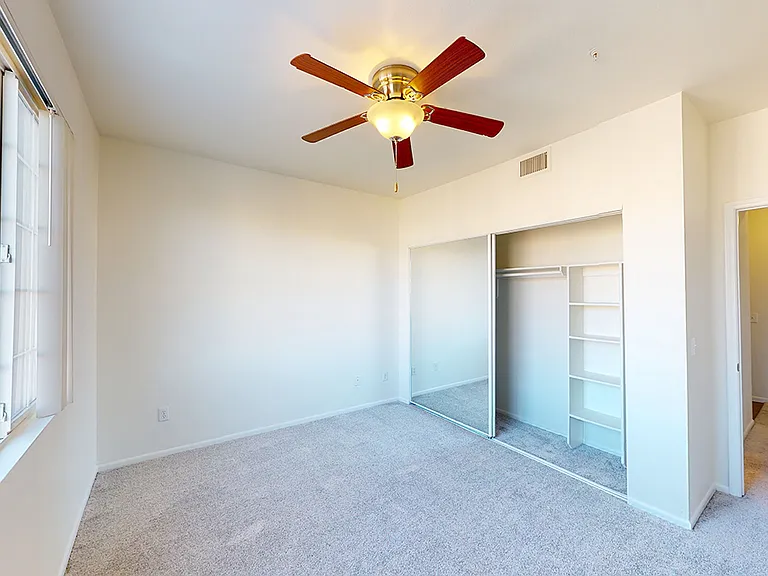 Spacious apartment bedroom with plush carpet flooring.