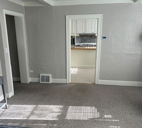 Walking into family room from outside with kitchen straight ahead and bathroom and bedroom 1 to the left