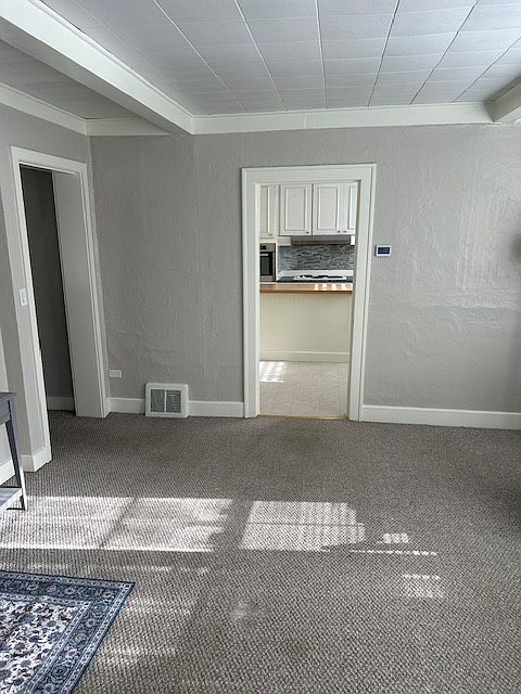 Walking into family room from outside with kitchen straight ahead and bathroom and bedroom 1 to the left