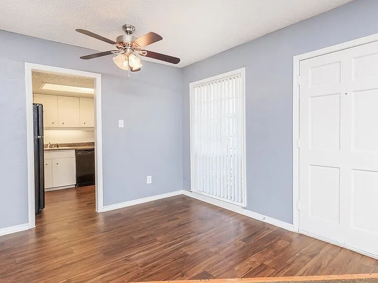 Spacious bedroom with wood-style flooring, large windows, and ample natural light.
