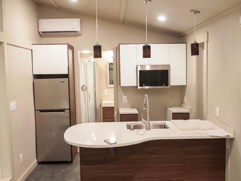 Kitchen boasts a dishwasher, gas range, microwave, dimmable pennant lighting, and under-mount sink. Energy-efficient ductless heat pump (seen above refrigerator) keeps the house cool in summer, warm in winter.