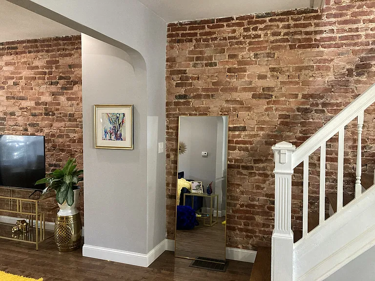 Exposed brick in living room and walls adjacent stairs leading to bedrooms, bathrooms, office and laundry room.
