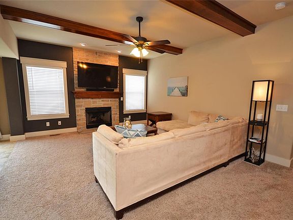 Great Room with wood beams add a touch of beauty and charm! Gas fireplace with stone style surround and custom mantle. Windows have casings and 2in blinds.
