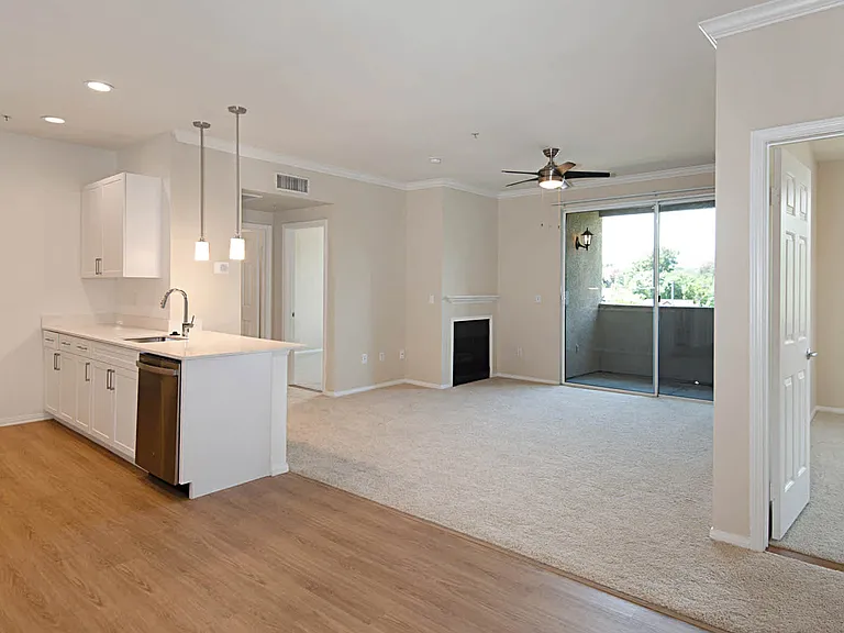 Kitchen and Carpeted Living Room with Fireplace and Balcony