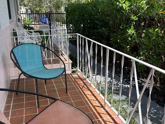 Private front porch with tropical landscaping and outdoor seating.