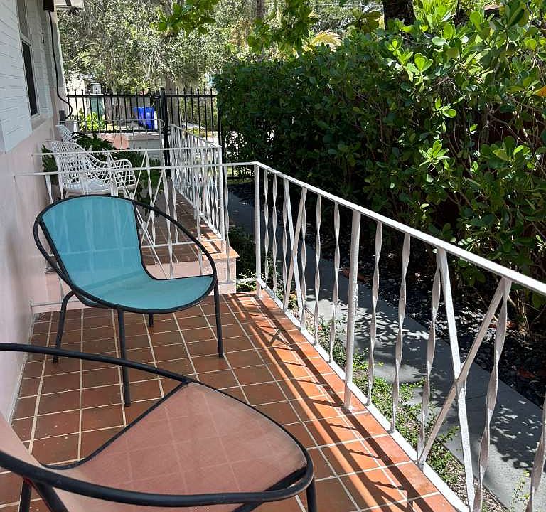 Private front porch with tropical landscaping and outdoor seating.