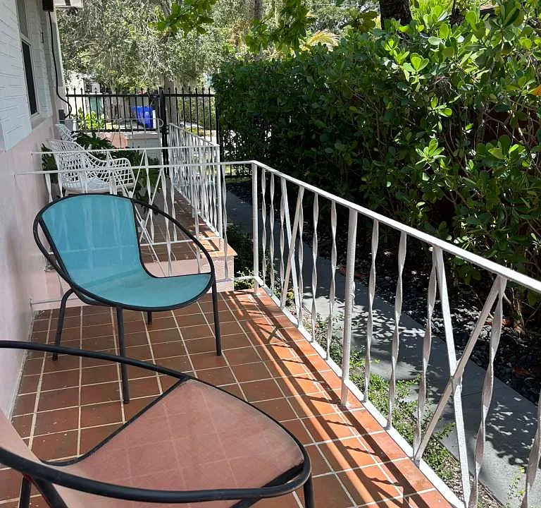 Private front porch with tropical landscaping and outdoor seating.