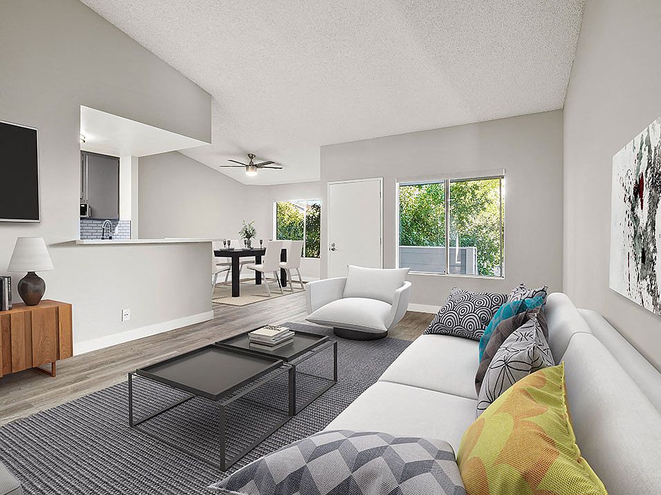 Hardwood floored living room with large windows and view of kitchen.
