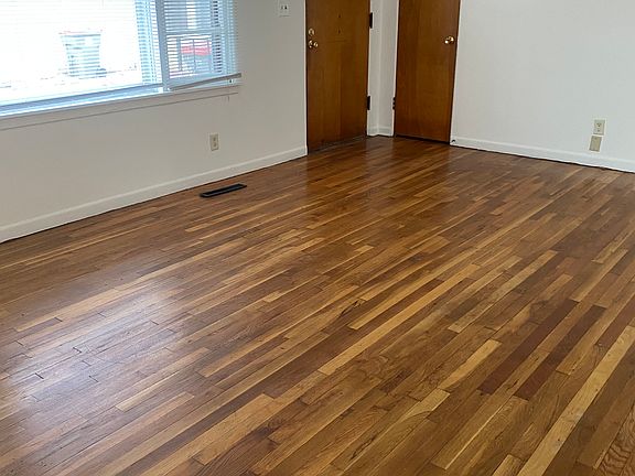 Living room with big windows letting in natural light. Beautiful hardwood floors and recently painted walls.