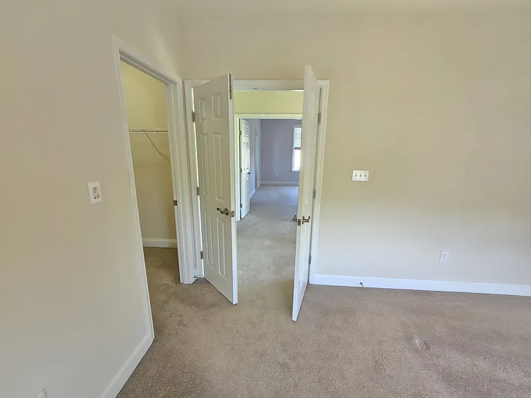 Another photo of third floor bedroom showing entrance on right to walk in closet and double doors to hallway.