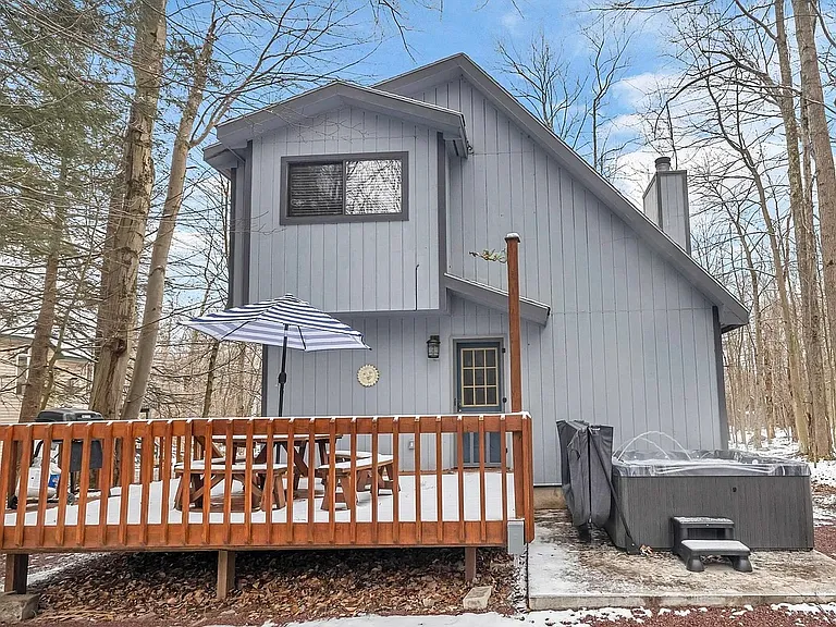 Backyard Deck & Hot Tub _ Relax and unwind on the spacious wooden deck featuring comfortable patio furniture, a gas grill for outdoor dining, and a private hot tub surrounded by a peaceful wooded setting.