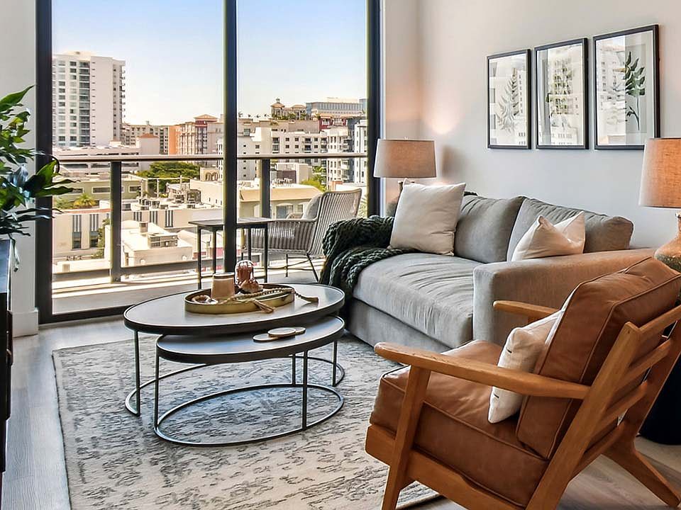 Griffis West Palm apartment living room with pattern rug, plush seating, framed art, and floor to ceiling window.
