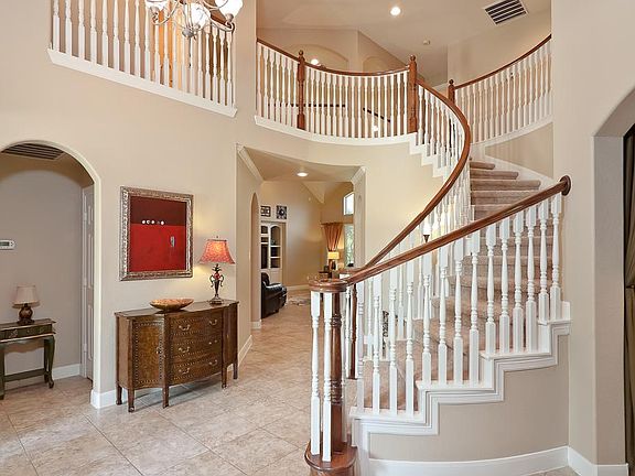 A dramatic soaring staircase with balcony views from above. This foyer provides ample space for accent furniture and art display.