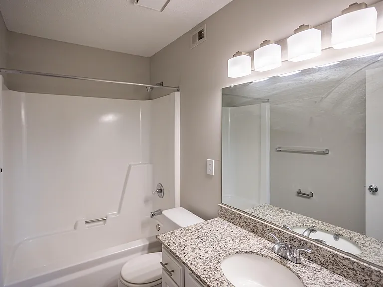 Bright bathroom with granite counters and bathtub