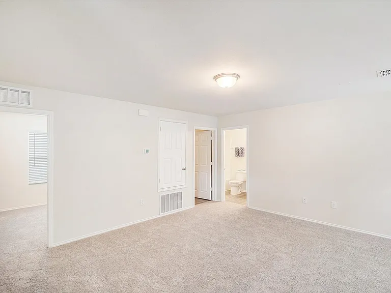 Spacious room with neutral-toned carpeting, white walls, and a flush-mount ceiling light fixture